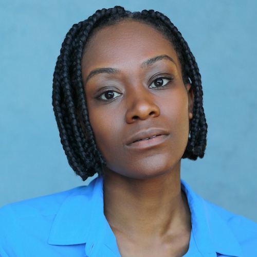 Cassiopeia Berkeley-Agyepong, a black woman with dark brown eyes looks to the camera. She wears a blue collared shirt and has black box braids styled into a bob.