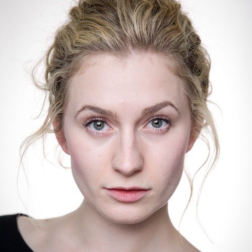 Sophie Clay, a white woman with blonde hair, wearing a black top looking at the camera. She had green eyes.